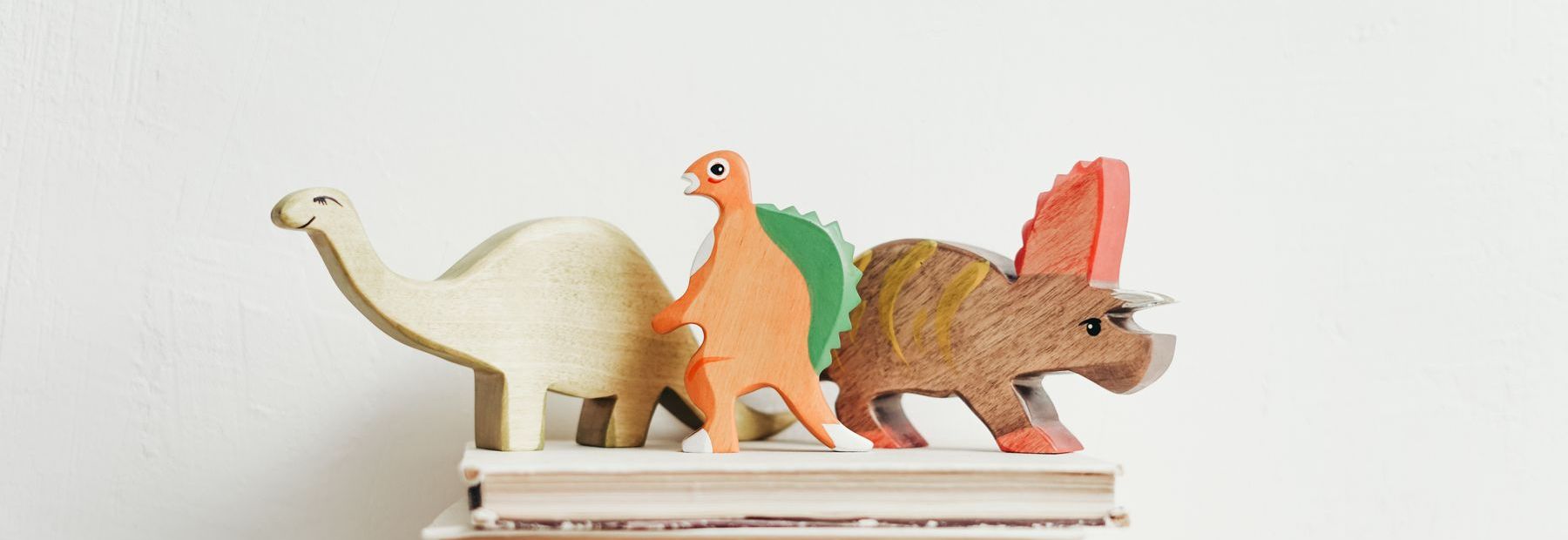 Drewniane figurki dinozaurów ustawione na stosie książek